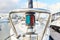 Close up of the bow of a sail boat in a marina, with lines, ropes and navigational lights in focus.