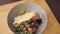 Close-up of bowl of cooked food meat and vegetables on wooden table in kitchen