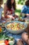 Close up of a bowl of salad on a picnic table with friends in the background