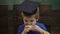 Close-up of a boy in graduation hat which eats an apple in a class. School break. Hungry kid eating apple in classroom