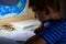 Close-up of boy hand with pencil writing English words. The boy writes his first test on English. Child writing