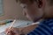 Close-up of boy hand with pencil writing English words. The boy writes his first test on English. Child writing