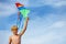 Close-up of a boy holding many kites in hand over blue sky