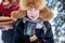 Close- up of a boy in a scarf, furs hat, coat and mittens, holding in his mouth a piece of a bitten pie