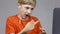 A close-up boy sits in front of a computer online about the conference and explains gestures to the teacher