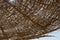 Close up of braided umbrellas. Sunshine through the rattan dome of beach umbrella. Summer sun in braided umbrella dome.