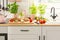 Close-up of bread, tomatoes and plants on a countertop in a kitchen interior