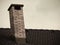 Close up on brick chimney on rooftop isolated in sky