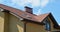 A close-up of a brick house with a brown asphalt shingled roof, soffit and fascia, skylight, chimney, attic skylight window and