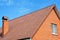 Close up on brick house red metal roof with chimney.