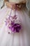 Close up of bride holding mini wedding bag with purple floral details