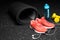 Close-up of bright training shoes, dumb-bells, rubber mat, blue bottle, and headphones on a black spotted background.