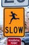 Close up of bright yellow Slow road sign with silhouetted image of running man