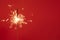 Close up of Brightly burning sparkler on a red background with lots of sparks