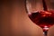 Close-up of brightly red wine poured in the wineglass and abstract splashing against brown background.