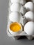 Close up broken egg yolk in carton packing on gray background