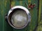 Close up of the broken headlight of an old abandoned truck with rusted green paintwork