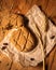Close-up broken homemade fresh bread, ear of ripe wheat, pumpkin seeds and raisins on parchment paper wooden table vertical photo