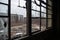 close-up of broken windows and doors, with the view of smokestacks and machinery in the background