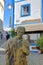 Close-up on a bronze statue representing a man standing on a cobbled street Porto Fundo with colorful buildings in the backgroun