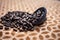 Close up of brown colored dried custard apples or sitaphal or sugar apple seeds in a black colored clay bowl on a brown colored su