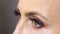 Close-up of brown eyes blinking. A young woman opens and closes her beautiful eye. Long black eyelashes. The eyelids are painted b