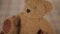 Close up of brown fluffy teddy bear placed into light small basket with toys.