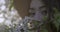 Close-up of brown hared girl with grey eyes wearing a hat and smelling the flowering branch of apple tree