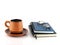 close up brown orange pottery coffee cup with saucer and two closed diary books (blue and black) with eyeglasses