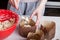 Close-up of brown paper baking tins filled with raw raisin dough and leveling it with a cooking muffin spoon at home