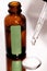 Close up of brown serum or oil glass with green stiker mock up on bottle on mirror background