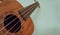 Close up of brown Ukulele on white background. Ukulele strings, saddle, soundhole, ukulele body, neck, fretboard.