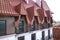 Close-up of building facade exterior with stucco wall, cast iron balcony railings, steep shingle roof and shiny windows