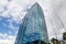 Close-up on a building with mirrored windows which reflects a blue sky with clouds. Business and construction