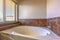 Close up of built in oval bathtub inside a bathroom with tiled and concrete wall