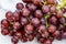 A close up of a bunch of juicy red grapes with stems on a white marble countertop, clean modern look