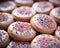 a close up of a bunch of pink frosted cookies with colorful sprinkles