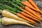 Close up of a bundle of carrots and parsnip on a rustic table