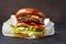 Close Up of Burger Piled High with Fresh Toppings on Whole Grain Artisan Bun, on a dark stone surface