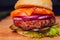 Close Up of Burger Piled High with Fresh Toppings on Whole Grain Artisan Bun, on Rustic Wooden Surface with Dark