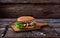 Close Up of Burger Piled High with Fresh Toppings on Whole Grain Artisan Bun, on Rustic Wooden Surface with Dark Background and Co