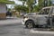 Close up a burned car in a parking lot with melted tire and no windows