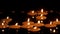 Close up burning candles floating on water surface in dark. Scented aroma candles float in dark water while relaxing spa