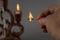 Close-up of a burning match in a man`s hand. A man`s hand holds a wooden match in front of a burning candle. Brown ceramic