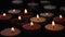 Close-up of burning tealight candle grouped together on black background