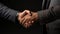 Close-up of a business Handshake between a mature hand with grey sleeve and a white mature hand with black sleeve