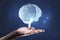 Close up of business man hand holding glowing human brain hologram on blurry wall background. Neurology research and artificial