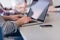 close up of business man hands typing on laptop with team on meeting in background