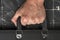 Close-up of a business man or worker`s hand holding the handle of a suitcase on a grunge background of crumpled black paper