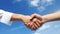 Close-up of business people shaking hands over blue sky background. Generative AI.